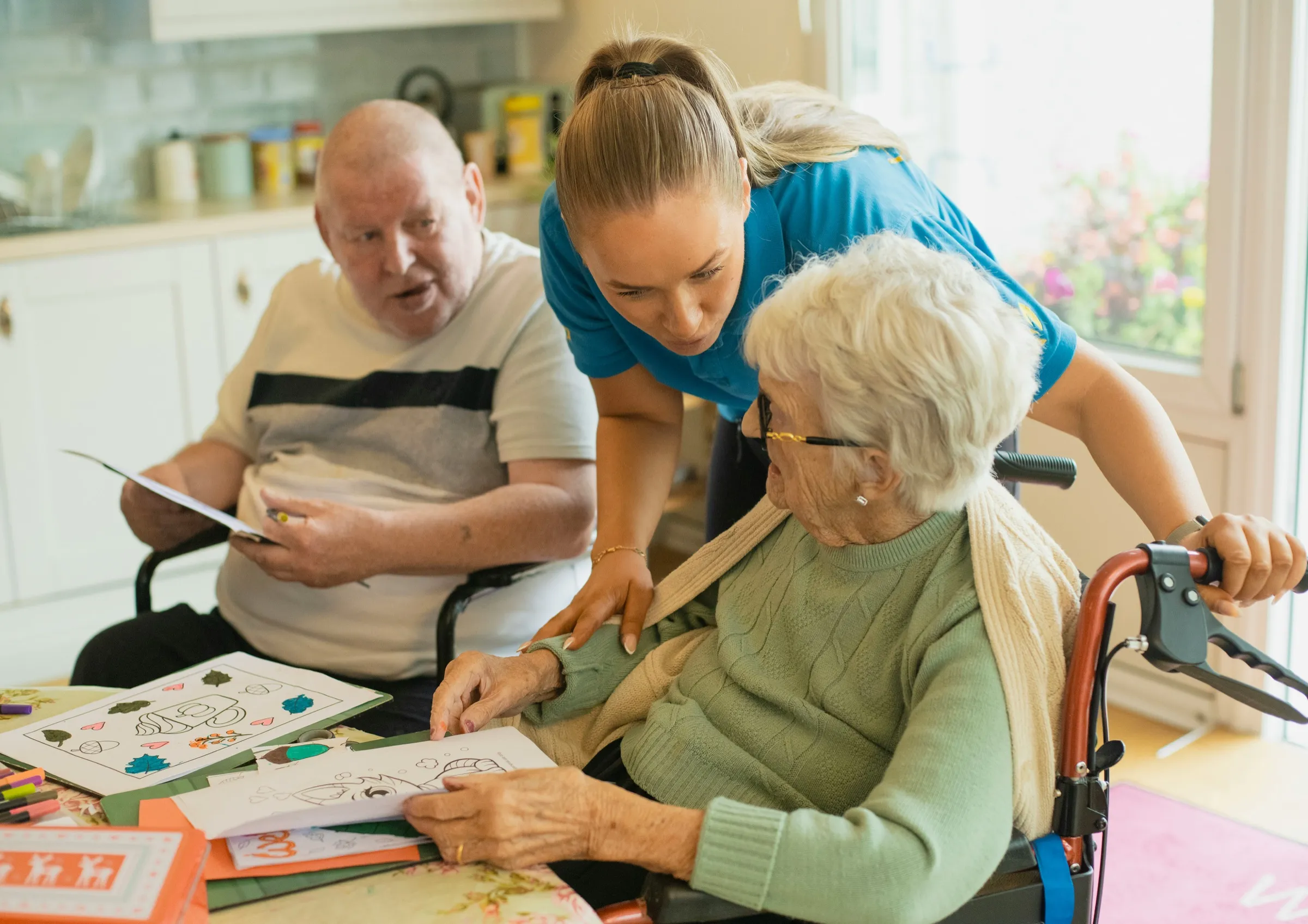 Zorgmedewerker met bewoners aan tafel
